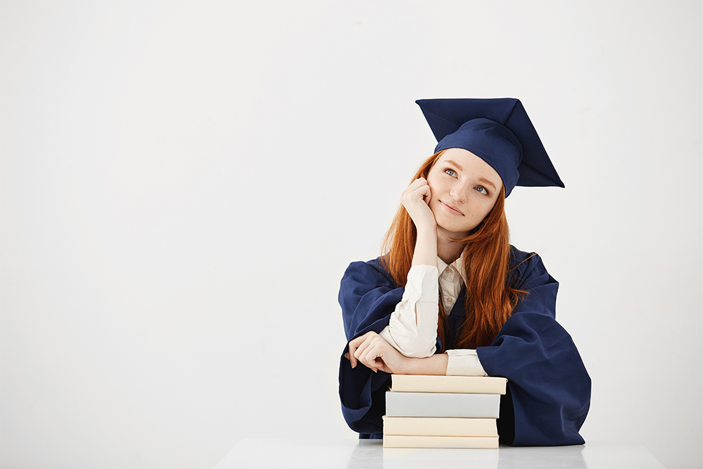 zamyślona studentka przy stosie książek