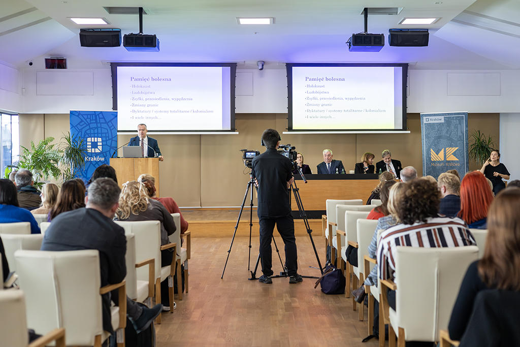 prof. dr hab. Łukasz Sroka podczas wygłaszania wykładu stoi przy mównicy, na pierwszym planie uczestnicy seminarium