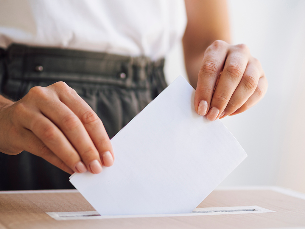 kobieta wkładająca kartę wyborczą do urny