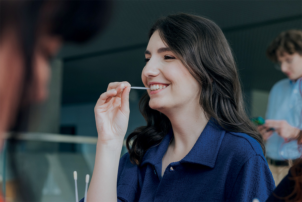 uśmiechnięta brunetka w granatowej bluzce podczas pobierania wymazu