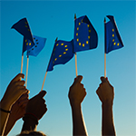 ludzie trzymający w&nbsp;dłoniach flagi UE