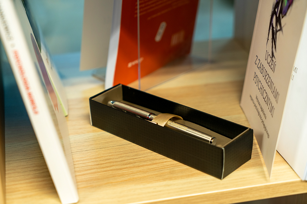 Powrót uniwersyteckiej księgarni (zdjęcie 3 z 4) pióro wieczne na tle publikacji Wydawnictwa Naukowego Uniwersytetu Pedagogicznego