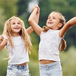 Dołącz do Uniwersytetu Dzieci i Rodziców. Rekrutacja na rok akademicki 2025/2026 grupa dzieci trzymających się za ręce uchwycona w podskoku